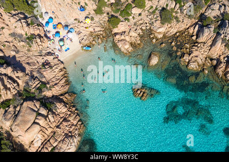 Ansicht von oben, einen atemberaubenden Blick auf einen kleinen Strand mit Sonnenschirmen und Menschen schwimmen im türkisblauen Wasser, Cala Coticcio, (Tahiti) Stockfoto