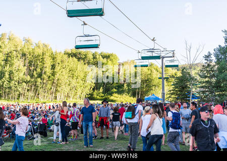 Aspen, USA - Juli 4, 2019: Snowmass Village Stadt und Leute auf der Skipiste hören kostenloses Konzert mit Lift Seilbahnen Stockfoto