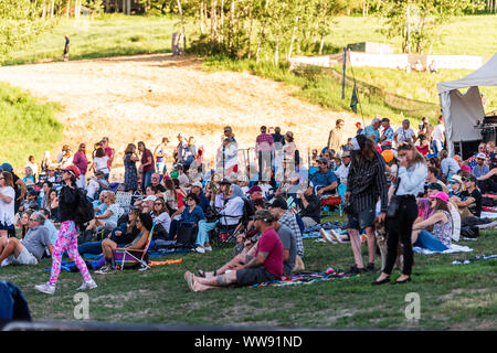 Aspen, USA - Juli 4, 2019: Snowmass Village Stadt und Leute sitzen auf Skipiste Gras hören kostenloses Konzert Stockfoto