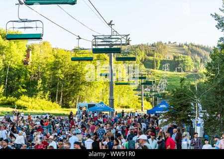 Aspen, USA - Juli 4, 2019: Snowmass Village Stadt und viele Menschen Gruppe Masse auf Skipiste hören kostenloses Konzert mit Lift Seilbahnen Stockfoto