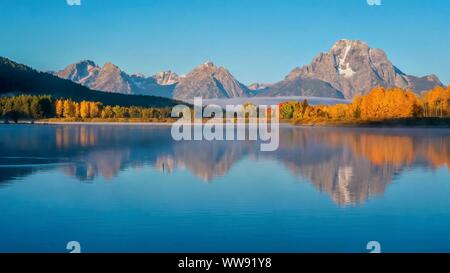 Eine wunderschöne Landschaft am frühen Morgen Szene an Oxbow Bend in der Snake River, mit Mount Moran und Herbst Baum Farbe im glatten Wasser wider. Gran Stockfoto