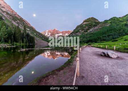 Maroon Bells See in Aspen, Colorado in der blauen Stunde der Dämmerung mit Rocky Mountain Peak und Schnee in Juli 2019 Sommer und Mond Reflexion Stockfoto