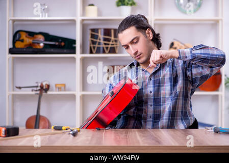 Die junge schöne Handwerker Reparatur Gitarre Stockfoto