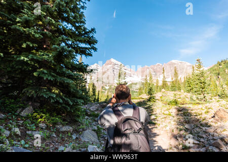 Maroon Bells Gipfelblick in Aspen, Colorado mit touristischen Mann Rucksack Wanderer mit Handy oder Kamera im Juli 2019 Sommer auf dem Weg weg weg w Stockfoto