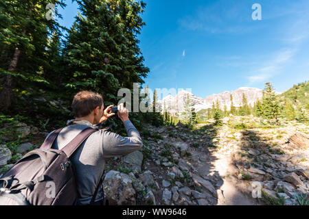 Maroon Bells peak in Aspen, Colorado mit touristischen Mann Rucksack Wanderer mit Kamera im Juli 2019 Sommer auf dem Weg weg weg großem Betrachtungswinkel Stockfoto