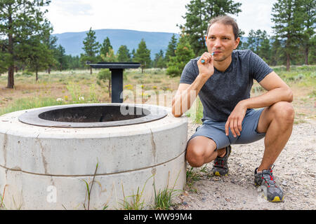 Campingplatz mit Mann die Zähne putzen, die von der Feuerstelle am Morgen auf Canyon Rim Campground in Utah Flaming Gorge National Park Stockfoto