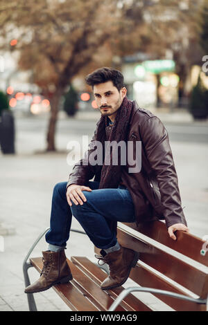 Nachdenklicher junger Mann sitzt auf einer Bank. Stockfoto