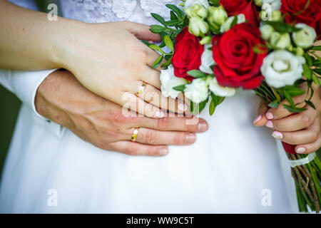 Bräutigam die Braut mit Hochzeit Rot Weiss Rose Bouquet. Ringe in den Händen der jungen Paare Stockfoto