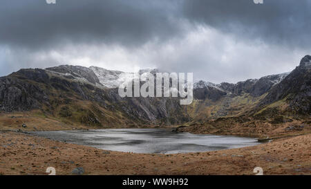 Atemberaubende dramatische Winterlandschaft Bild von Llyn Glyders Idwal und schneebedeckten Bergkette in Snowdonia Stockfoto