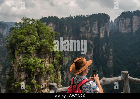 Zhangjiajie, China - August 2019: Touristen bewundern die Aussicht und die Bilder auf dem Smartphone auf der Brücke Himmel Säule Viewpoint, Avatar moun Stockfoto