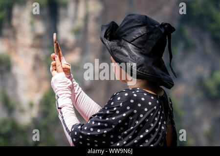 Zhangjiajie, China - August 2019: Weibliche Tourist, der selifie Bilder auf Handy auf den Blickwinkel in Tianzi mountain range, Avatar Berge Stockfoto