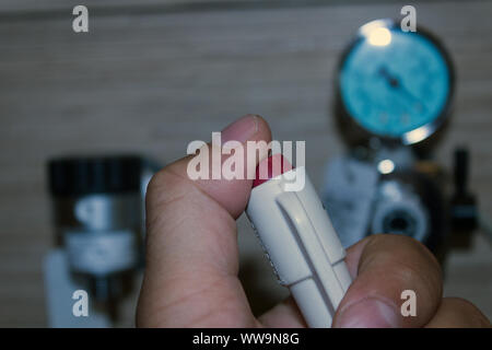 Nahaufnahme der Hand eines Mannes, Druck auf eine rote Taste mit Daumen im Krankenhausraum mit verschwommenen Sauerstoff-Hilfsmitteln im Hintergrund. Stockfoto