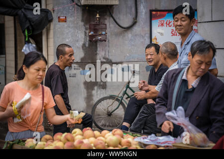 Xian, China - Juli 2019: Gruppe von männlichen Freunden reden und Chatten hinter einer Frucht im muslimischen Viertel in Xian, Provinz Shaanxi Stadt Abschaltdruck Stockfoto