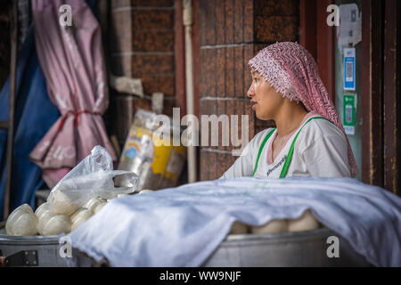 Xian, China - Juli 2019: muslimische Frau verkaufen baozi Brötchen und Teig auf die Lebensmittel Straße im muslimischen Viertel Stockfoto