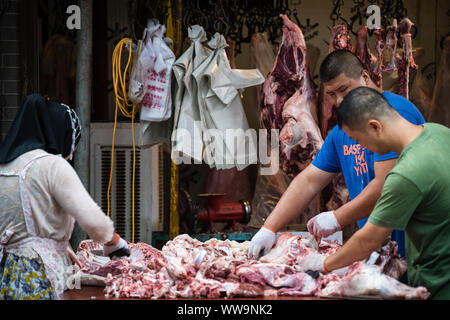 Xian, China - Juli 2019: Zwei Männer Arbeiter schneiden und die Trennung von Lamm und Rind Karkasse Fleisch und Knochen, die Street Food Anbietern im muslimischen Viertel Stockfoto