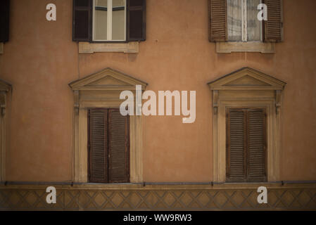 Rom, Italien, 5. Juli 2018: Verschlissene braunen Fensterläden sind auf einem hellen orange Gebäude in der Innenstadt von Rom im Sommer geschlossen. Stockfoto