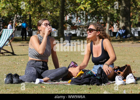 St James's Park, London, UK, 13. September 2019 - Frauen sitzen auf dem Boden im St James's Park an einem warmen und sonnigen Tag in der Hauptstadt. Nach dem Met Office, die Temperatur ist auf 25 Grad Celsius dieses Wochenende in vielen Teilen von Großbritannien. Credit: Dinendra Haria/Alamy leben Nachrichten Stockfoto