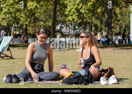 St James's Park, London, UK, 13. September 2019 - Frauen sitzen auf dem Boden im St James's Park an einem warmen und sonnigen Tag in der Hauptstadt. Nach dem Met Office, die Temperatur ist auf 25 Grad Celsius dieses Wochenende in vielen Teilen von Großbritannien. Credit: Dinendra Haria/Alamy leben Nachrichten Stockfoto