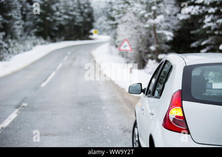 Weißes Auto auf einem Winter weg durch einen verschneiten Wald. Seitenansicht Stockfoto