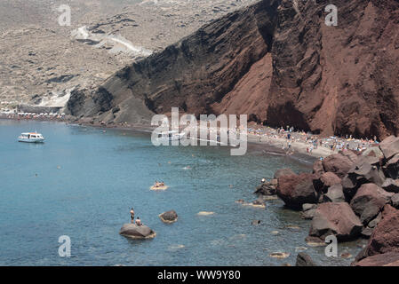 Santorini, Griechenland - 24. Juni 2018: Menschenmassen und Boote auf Roten Strand, ein beliebtes Reiseziel an der Südküste von Santorin. Stockfoto
