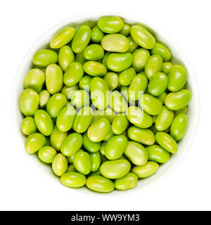 Edamame. Grüne Sojabohnen in weiße Schüssel. Mukimame, unreife Sojabohnen außerhalb des Pod. Glycine max, ein Legumen, essbare nach dem Kochen und eine Proteinquelle. Stockfoto