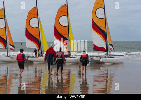 Segelboot und Touristen an einem Strand in der Bretagne im Sommer Stockfoto
