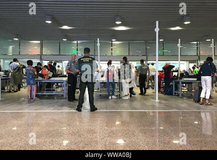 Barcelona, Spanien - 10. September 2019: Passagiere Line up an der Sicherheitskontrolle von Barcelona Flughafen, während ein Wachmann beobachtet die Szene Stockfoto