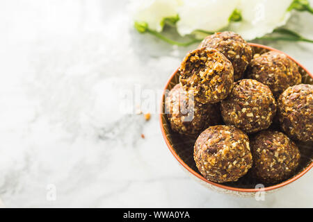 Energie protein Kugeln mit gesunden Zutaten auf Marmor tisch. Home gemacht mit Termine, Peanut Butter, Flachs und Chia Samen-, Hafer-, Mandel- und Schokolade dr Stockfoto