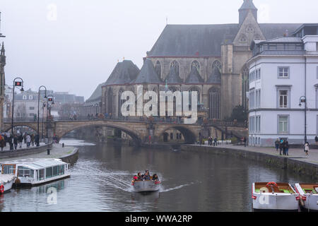 Touristen fahren Sie den Kanal in der Nähe von St. Michael's Bridge (Sint-Michielsbrug) und die Kirche St. Michael (sint-michielskerk) im nebligen Winter morgen. Stockfoto