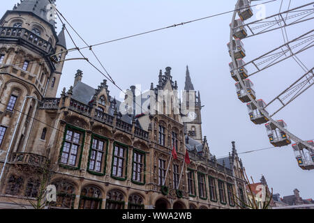 Riesenrad in der Innenstadt von Gent in der Nähe des Gotischen alten Postgebäude in nebligen Winter morgen gegen kalten grauen Himmel. Stockfoto