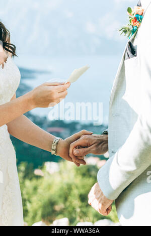 Die Braut liest ihren Eid zu pflegen und sie halten die Hände. Stockfoto