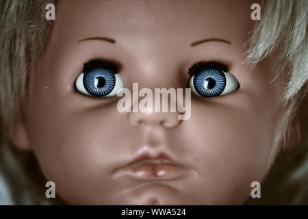 Gruselig und düster den Kopf. Ein furchtsames Gesicht einer blonden Baby Vintage Doll mit blauen Augen Stockfoto