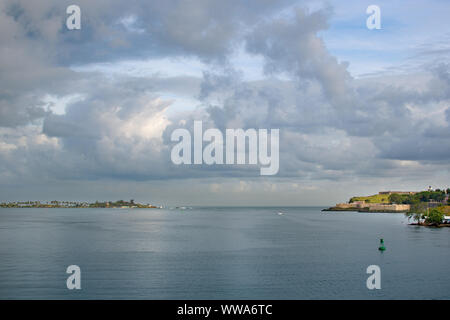 Blick auf San Juan Bay und Fort San Felipe del Morro in pre-Sturm Wetter. Dichten Gewitterwolken und Sonnenstrahlen im Meer wider. Stockfoto