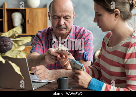 Olderly spanische Mann gibt seine Tochter Geld für eine Hypothek oder Darlehen. Hilfe für Kinder und Rentner. Stockfoto