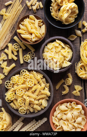 Vielfalt von Arten und sshapes trockener italienischer Pasta in Schalen mit dunklen Holzmöbeln im Landhausstil Hintergrund Stockfoto