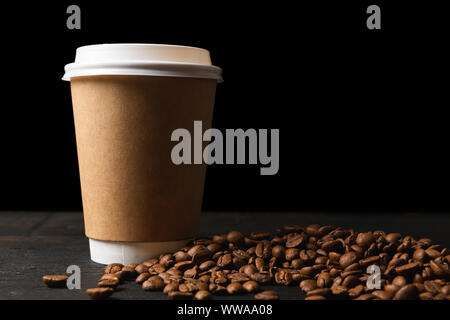 Papier Tasse Kaffee und Kaffeebohnen auf dunklen Holztisch. Gute Qualität Stockfoto