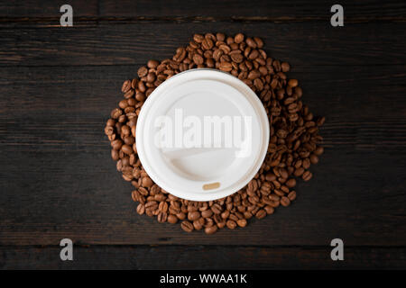 Papier Tasse Kaffee und Kaffeebohnen auf dunklen Holztisch. Gute Qualität Stockfoto