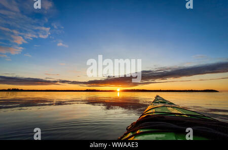 Ein Kajak paddeln bei Sonnenuntergang, ruhigem Wasser. Stockfoto
