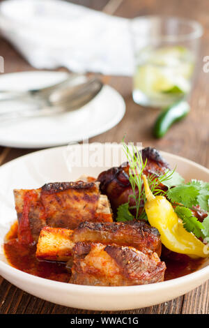 Gegrilltes Rindfleisch geschmorte Rippchen serviert mit Chili jalapeno und frischen Kräutern auf Holzbrett Stockfoto