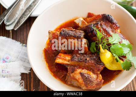 Gegrilltes Rindfleisch geschmorte Rippchen serviert mit Chili jalapeno und frischen Kräutern auf Holzbrett Stockfoto