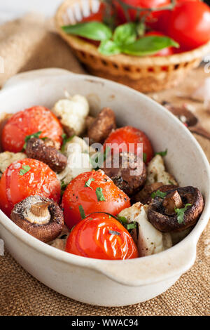 Verschiedene Gemüse im Ofen gebacken in Keramik Schüssel. Gegrillte Tomaten, Champignons, Blumenkohl Stockfoto