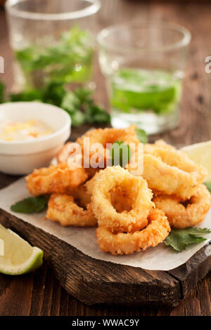 Frittierte calamari Ringe auf Holz Schneidebrett mit Zitrone und Petersilie Stockfoto