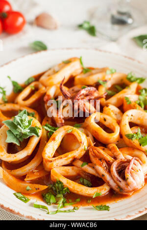 Salat mit Calamari, Octopus, Petersilie und Tomatensauce auf hellem Holztisch Stockfoto