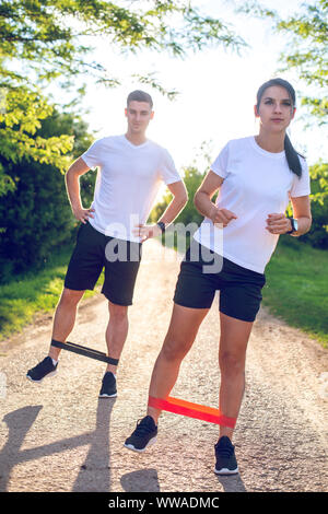 Junges Paar Trainieren mit elastischer Widerstand Band draußen im Park Stockfoto