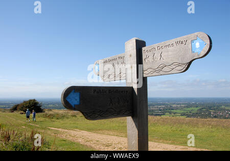 South Downs, Sussex, England, UK. Ein Mann und eine Frau auf dem South Downs Way in Sussex. Ein Wegweiser zeigt die Route der South Downs Way. Stockfoto