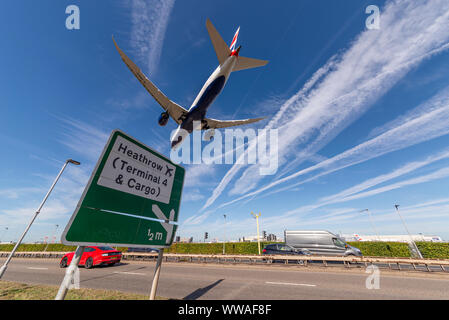 British Airways Jet Airliner landet am Flughafen London Heathrow in Hounslow, London, UK über die A30 mit Verkehr und Schild Stockfoto