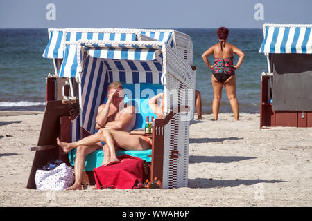 Menschen in einem Strandkorb Stuhl geniessen Sie einen sonnigen Nachmittag am Strand von Warnemünde Deutschland Ostsee Urlaub Stockfoto