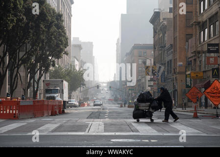 San Francisco, Kalifornien - 17. November 2018: ein Obdachloser treibt ein Warenkorb Silhouette, als er 2. Straße an der Ecke Markt kreuzt. Stockfoto