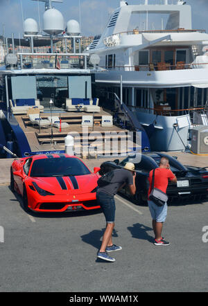 Zwei Männer, die Fotos von Sportwagen durch die Luxusyacht auf der Mole im Hafen von Cannes, Cote d'Azur, Frankreich, EU geparkt. Stockfoto