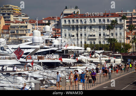 Menschen zu Fuß am Kai von Luxus Motoryachten mit dem Hotel Splendid in den Hintergrund in Cannes, Côte d'Azur, Frankreich, EU Stockfoto